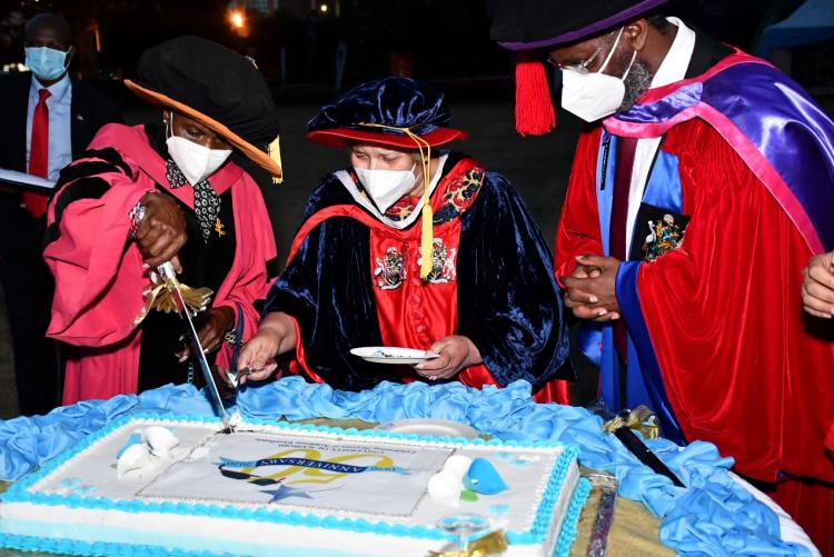 Chancellor Dr Vijoo Rattansi VC Prof Stephen Kiama look on as Council Chair Prof Julia Ojiambo cuts the UoN@50 cake