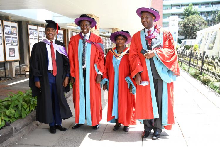 Muranga Senator Irungu Kangata (R) who graduated with a PhD poses with faculty and one of the graduands