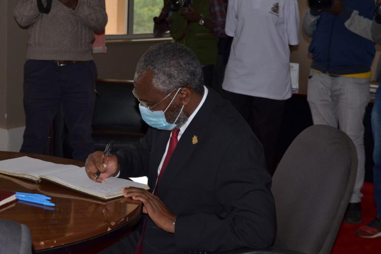 UoN Vice Chancellor Prof Stephen Kiama signs the visitors book before the tree planting exercise